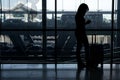 Silhouette of girl with luggage stand near window in airport