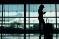 Silhouette of girl with luggage stand near window in airport