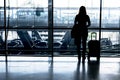 Silhouette of girl with luggage stand near window in airport