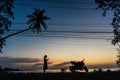 Silhouette of girl with phone and motorcycle on sunset background on tropical island among palm trees Royalty Free Stock Photo