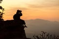 Silhouette girl photographer sitting on the rocks at high shooting at sunset. Royalty Free Stock Photo