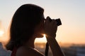 Silhouette of girl photographer taking picture setting sun on compact camera. sunset background Royalty Free Stock Photo