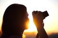 Silhouette of girl photographer taking picture setting sun on compact camera. sunset background Royalty Free Stock Photo