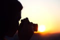 Silhouette of girl photographer taking picture setting sun on compact camera. sunset background Royalty Free Stock Photo