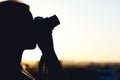 Silhouette of girl photographer taking picture setting sun on compact camera. sunset background Royalty Free Stock Photo
