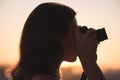 Silhouette of girl photographer taking picture setting sun on compact camera. sunset background Royalty Free Stock Photo