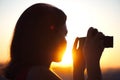 Silhouette of girl photographer taking picture setting sun on compact camera. sunset background Royalty Free Stock Photo