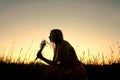 Silhouette of Girl Picking Flowers in Meadow at Sunset