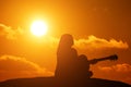 Silhouette of girl playing the guitar on the background of the sea and a beautiful sunset Royalty Free Stock Photo