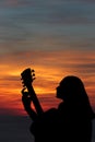 Silhouette of girl playing the guitar on the background of the sea and a beautiful sunset Royalty Free Stock Photo