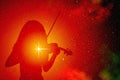 The silhouette of a girl playing the violin against a background of colorful outer space with bright stars and nebulae