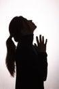 Silhouette girl raised her head up asking for help on white isolated background, young woman in black clothes praying Royalty Free Stock Photo