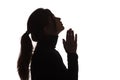 Silhouette girl raised her head up asking for help on white isolated background, young woman in black clothes praying Royalty Free Stock Photo