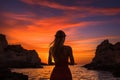 Silhouette of a girl in a red dress on the beach at sunset, Epic red sunset in Cala Llentrisca with a model, Ibiza, AI Generated