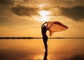 Silhouette of a girl in a red swimsuit on the beach. Red tissue develops in her hands Royalty Free Stock Photo