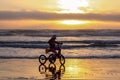 Silhouette of a girl riding tricycle on a beach in a starting tide