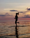 silhouette of a girl run on the beach sand. Shooting against the sun. Sunset over the sea Royalty Free Stock Photo