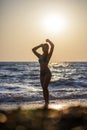 Silhouette of a girl at sea, vacation vitality healthy living concept. Lonely woman standing on the beach sunset. Royalty Free Stock Photo