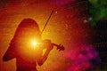 Silhouette of a girl with a shining star and a violin, against a background of colorful outer space with musical notes