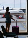 SILHOUETTE: Girl in shorts looks through the window while waiting her flight. Royalty Free Stock Photo