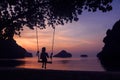 Silhouette of a girl sitting on a swing or cradle on the beach at sunset Royalty Free Stock Photo