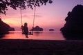 Silhouette of a girl sitting on a swing or cradle on the beach at sunset Royalty Free Stock Photo