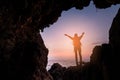 Silhouette of a girl standing in front of the entrance to the cave. Freedom concept. Woman Christians raising their hands in Royalty Free Stock Photo