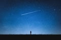 Silhouette of girl standing on mountain and night sky with shooting star. Alone concept