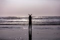 Silhouette of a girl standing in an ocean waves with hands up forming bird wings Royalty Free Stock Photo