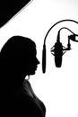 Silhouette of a girl with a studio microphone, Radio presenter, singer and blogger, voice acting for films. Strong, black and Royalty Free Stock Photo