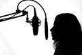 Silhouette of a girl with a studio microphone, radio presenter, singer and blogger, voice acting for films. Strong, black and Royalty Free Stock Photo