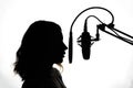 Silhouette of a girl with a studio microphone, radio presenter, singer and blogger, voice acting for films. Strong, black and Royalty Free Stock Photo