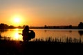 Silhouette of a girl at sunrise playing the guitar by the river Royalty Free Stock Photo