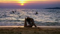 Silhouette of a girl at sunset, against the background of the sea, slender leggy girl funny doing gymnastic coups on the Royalty Free Stock Photo