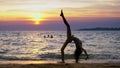Silhouette of a girl at sunset, against the background of the sea, slender leggy girl funny doing gymnastic coups on the Royalty Free Stock Photo