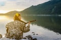 Silhouette of a girl at sunset playing the guitar by the river Royalty Free Stock Photo