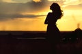 Silhouette of girl at sunset in summer field, a young woman enjoying nature Royalty Free Stock Photo