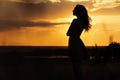 Silhouette of girl at sunset in summer field, a young woman enjoying nature Royalty Free Stock Photo