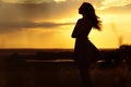 Silhouette of girl at sunset in summer field, a young woman enjoying nature Royalty Free Stock Photo