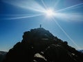 Silhouette of a girl on top of of the Penalara mountain in Spain with the sun shining in the sky