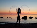 Silhouette of a girl who twists hula-hoops on the sandy shore during sunset Royalty Free Stock Photo