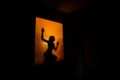Silhouette of a girl's slim figure against a window with orange light