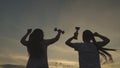 silhouette of girls winners jumping from happiness with golden cups their hands, sportswomen who won competition sunset Royalty Free Stock Photo