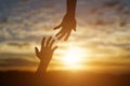 Silhouette of giving a helping hand, hope and support each other over sunset background Royalty Free Stock Photo