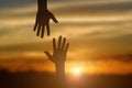 Silhouette of giving a helping hand, hope and support each other over sunset Royalty Free Stock Photo