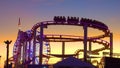 SILHOUETTE: Golden evening sunbeams illuminate rollercoaster and ferris wheel.