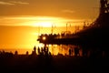 SILHOUETTE: Evening sun rays illuminate Santa Monica Pier and tourists on beach
