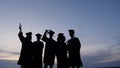 Silhouette of graduates with certificates on a sunset background