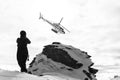 Silhouette grayscale shot of a person watching Heliskiing drop off on the ridgeline of Alps Peak