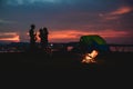 Silhouette  group of Asian friends tourist drinking and playing guitar together with happiness in Summer while having camping near Royalty Free Stock Photo